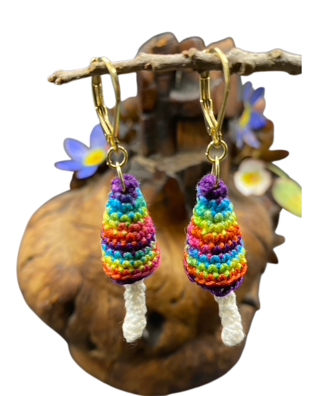 Colorful crocheted earrings hanging from a branch with a natural background